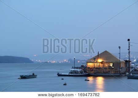 BELGRADE SERBIA - MARCH 7 2015: Restaurant-boat (splav in Serbian) on Danube river taken from the disctrict of Zemun in the evening. City center of Belgrade can be seen in the background