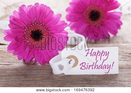 Label With English Text Happy Birthday. Pink Spring Gerbera Blossom. Vintage, Rutic Or Aged Wooden Background. Card For Spring Greetings.