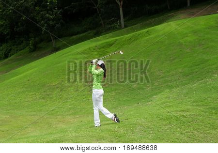 Women player golf swing shot on course in summer - Sports concept greenery tone