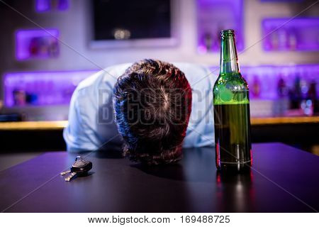 Depressed drunk man sleeping with his head on the table in bar