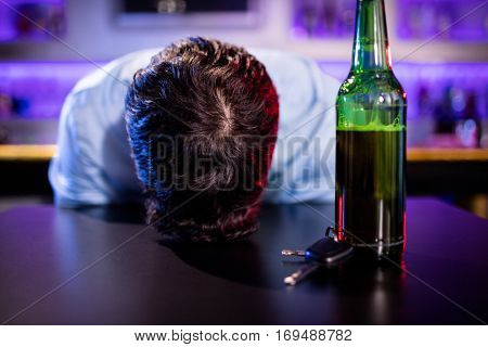 Depressed drunk man sleeping with his head on the table in bar