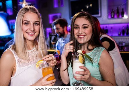 Portrait of smiling friends having cocktail at bar counter in bar
