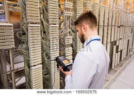 Technician using digital cable analyzer in server room