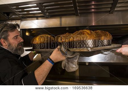 Baker taking out baked panettone from oven