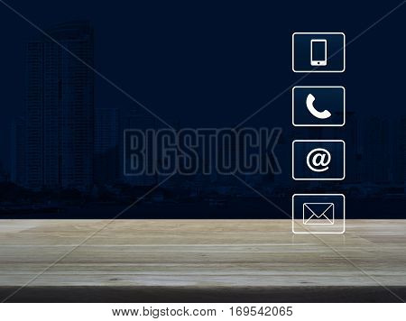 Telephone mobile phone at and email buttons on wooden table over modern office city tower Customer support concept