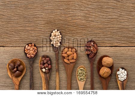 Different kind of beans and lentils in wooden spoon on wood background. mung bean groundnut walnuts macadamia almond soybean red kidney bean black bean sesame corn red bean and brown pinto beans