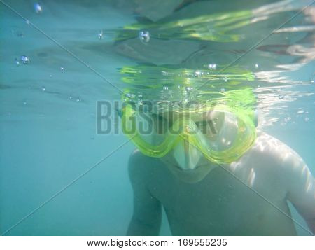 Kid in the mask for the snorkel surveys the bottom of the sea,
underwater photography