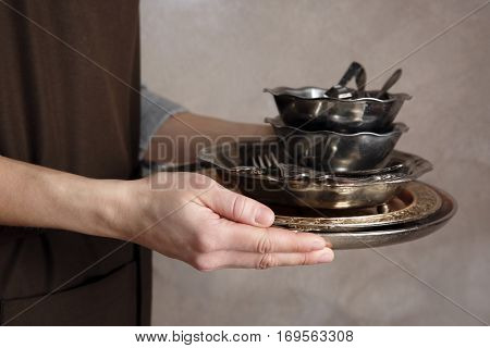 Closeup of woman holding tray with silver dishware