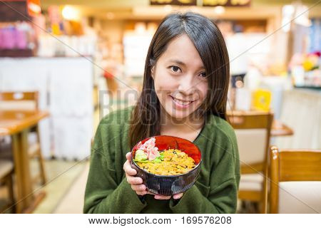 Woman enjoy urchin rice bowl in Japanese restaurant
