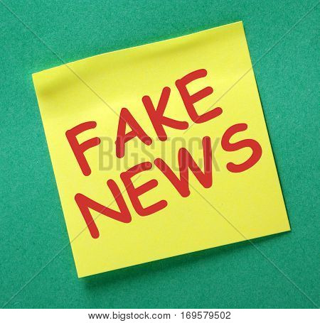 The words Fake News in red text on a yellow sticky note as a reminder to be aware of hoaxes and disinformation for propaganda uses