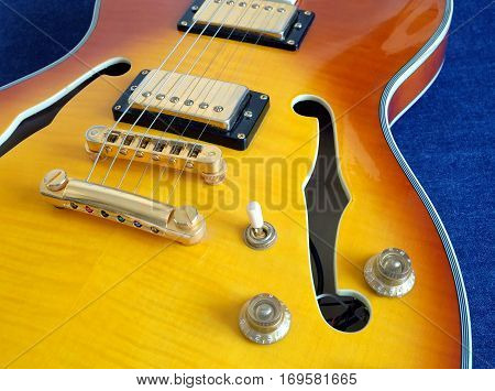 Part of vintage semi-hollow body electric guitars with pickups, electronics knobs and metal accessories on jeans background closeup
