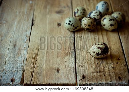 Scattered quail eggs on aged planked wood background, rustic vintage style, minimalist, kinfolk, Easter, tranquility and simplicity concept