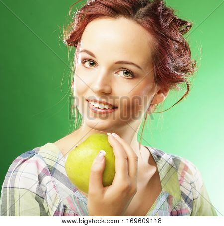 Young happy smiling woman with green apple. Studio shot over green background.