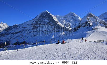 Ski and snow covered mountains Eiger Monch and Lauberhorn. Winter day in Grindelwald Swiss Alps.
