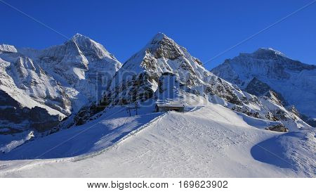 Snow covered mountains Monch Lauberhorn and Jungfrau. Chair lift and ski slope. Winter landscape in Grindelwald Swiss Alps.