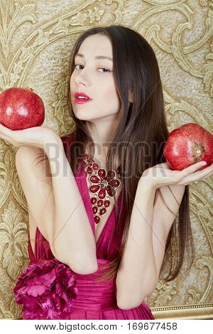 Portrait of young girl with two pomegranites in hands.