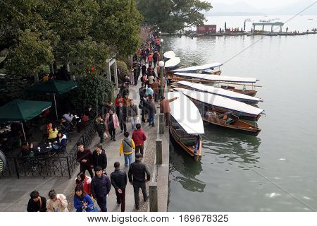 HANGZHOU - FEBRUARY 21: Crowd of tourists and boatmen on West Lake coast, famous park in Hangzhou city, China, February 21, 2016.