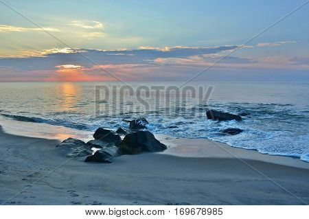 Summer Seashore Sunrise Over a Rock Jetty on the Beach