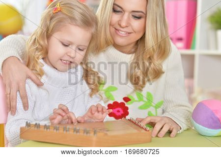 mother with little daughter playing on instrumen
