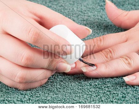 Woman using transparent nailpolish during making manicure herself