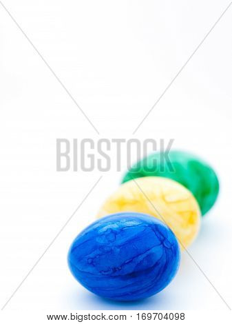 Three painted Easter eggs: blue, yellow and green.