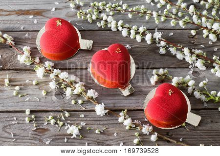 Red heart cacke desserts and sakura on wooden background. dessert for breakfast on Valentine's Day.