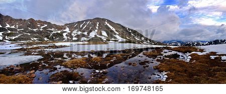 Panorama of mountanis and reflection in water. Snow thawing on Independence Pass. Aspen. Colorado. United States.