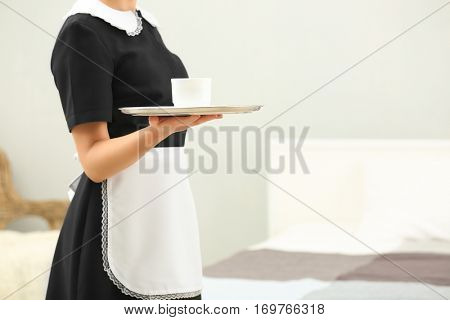 Hotel service concept. Chambermaid holding tray with cup of coffee