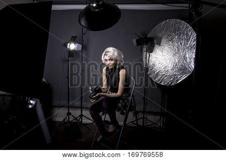 Creative female professional photographer in a strobe lighting studio. She portrays an independent self employed freelance entrepreneur. The image depicts the photography arts.