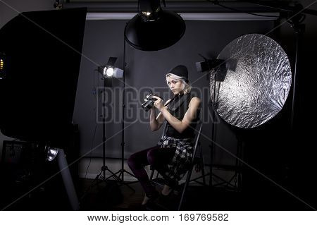 Creative female professional photographer in a strobe lighting studio. She portrays an independent self employed freelance entrepreneur. The image depicts the photography arts.