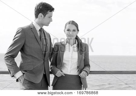 Portrait of businesswoman with coworker leaning on terrace railing against sky