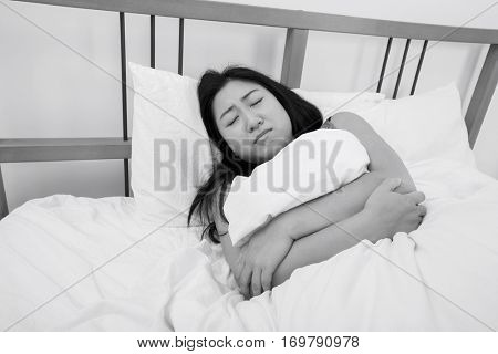 Young woman suffering from stomach ache lying in bed