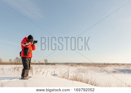 photographer takes winter landscape at dawn in the bitter cold.