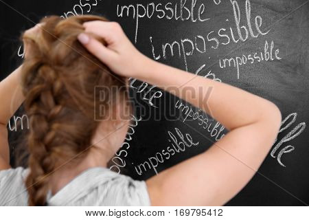 Girl thinking in front of chalk board