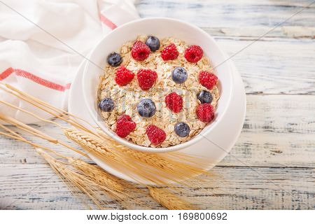 Oatmeal being garnished with fresh berries blueberries and raspberry