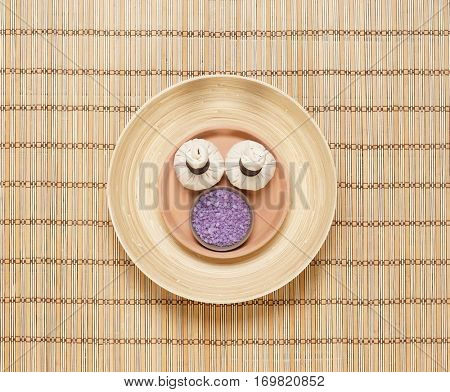 Massage bundle on a plate with bath salt over bamboo mat. Spa, health, treatment concept.