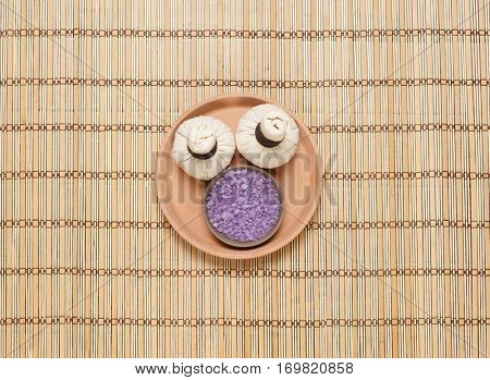 Massage bundle on a plate with bath salt over bamboo mat. Spa, health, treatment concept.