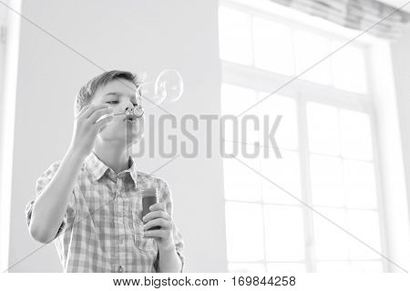 Boy blowing bubbles at home