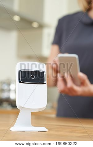 Woman Controlling Smart Security Camera Using App On Mobile Phone