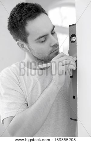 Mid-adult man marking on wall with level