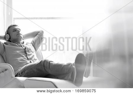 Full-length of relaxed Middle-aged man listening to music at home