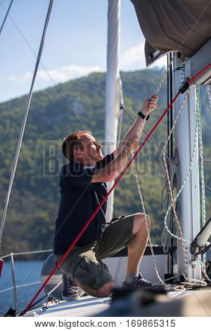 Sailing, man pulling ropes. Luxery yacht boat.