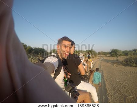 Couple taking a selfie in a camel riding in desert - with Gopro Camera