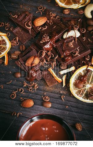 Chocolates background. Chocolate. Cup of hot chocolate lemon nuts and assortment of fine chocolates in dark and milk chocolate on dark wooden table