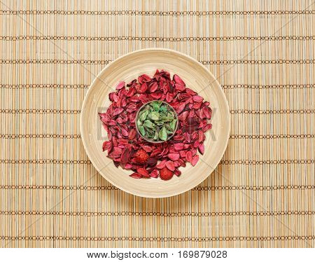 Plate with aroma petals on bamboo mat. Spa, beauty, treatment concept. 