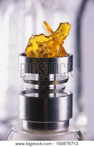 Piece of cannabis oil concentrate aka shatter over a titanium rig isolated over white background