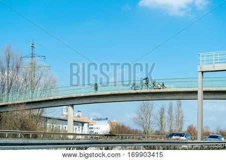 STUTTGART GERMANY - MAR 26 2016: People walking on pedestrian bridge passage above German autobahn highway on a spring warm day