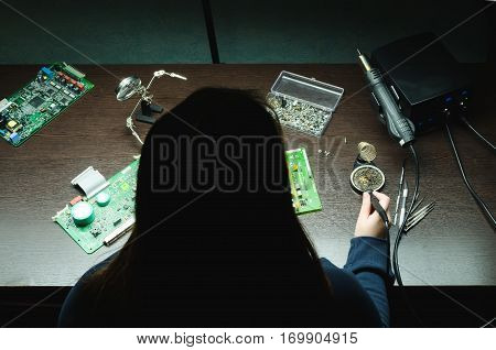 Young woman technician repair electronics device use soldering iron