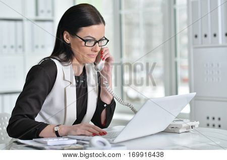 young brunette woman working at office, using laptop