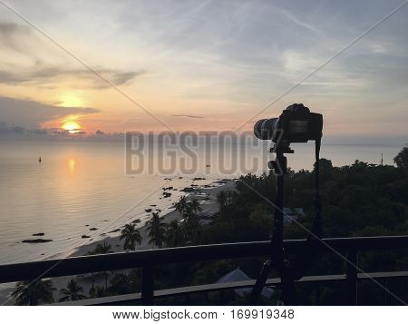 camera on tripod take sunrise picture over sea and beach at Hua Hin Thailand in warm tone